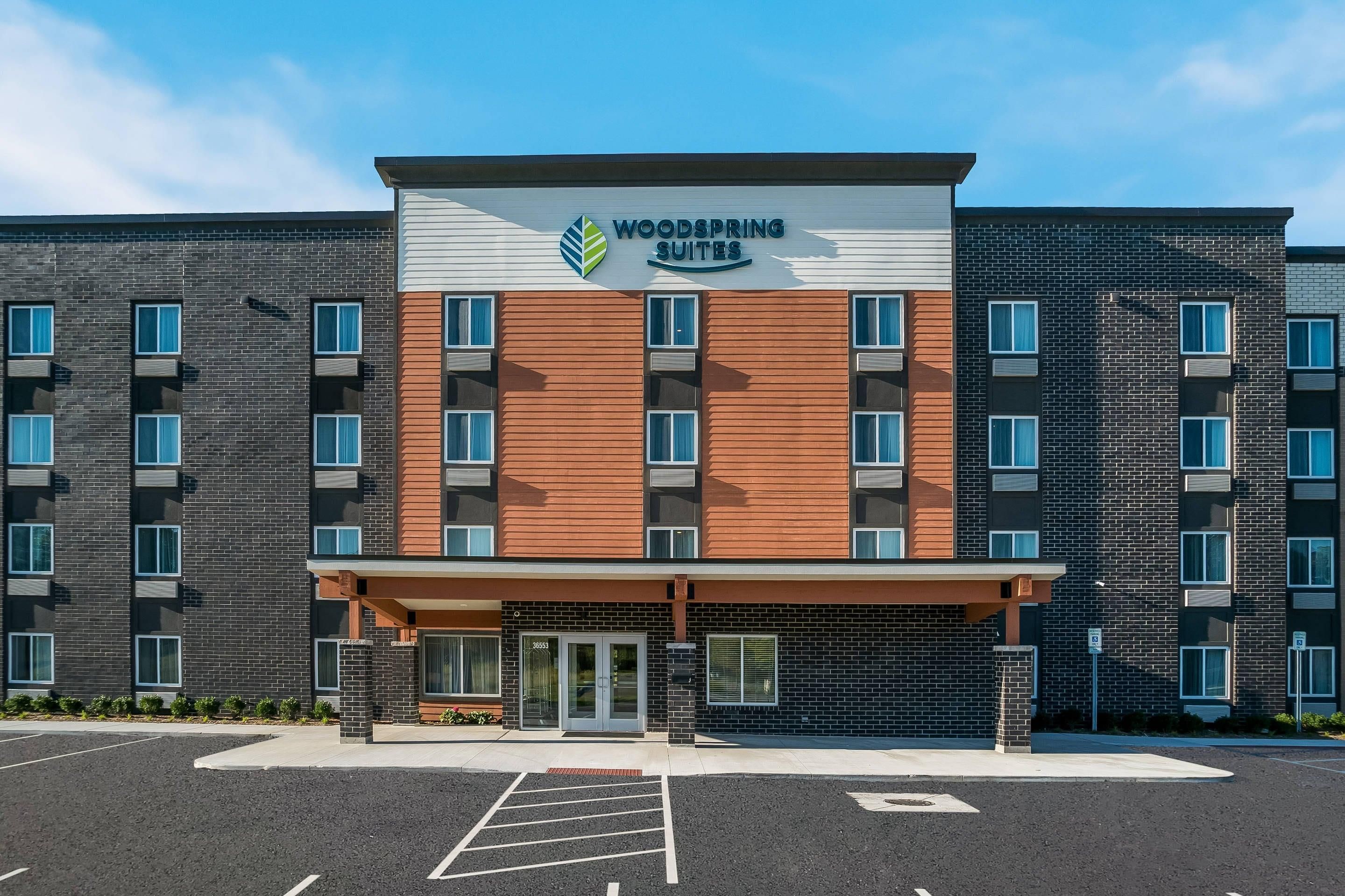 A multi-story hotel with a modern facade, featuring a mix of brick and wood paneling, large windows, and a clear entrance.