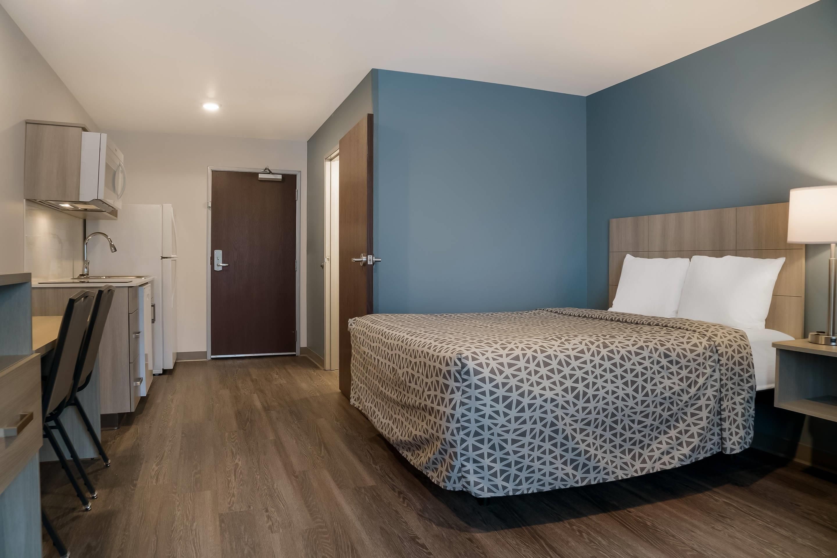 A hotel room with a bed, a desk, and a wardrobe.