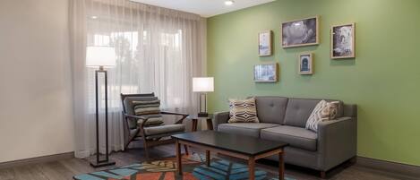 A modern living room with a sofa, armchair, coffee table, and a patterned rug.