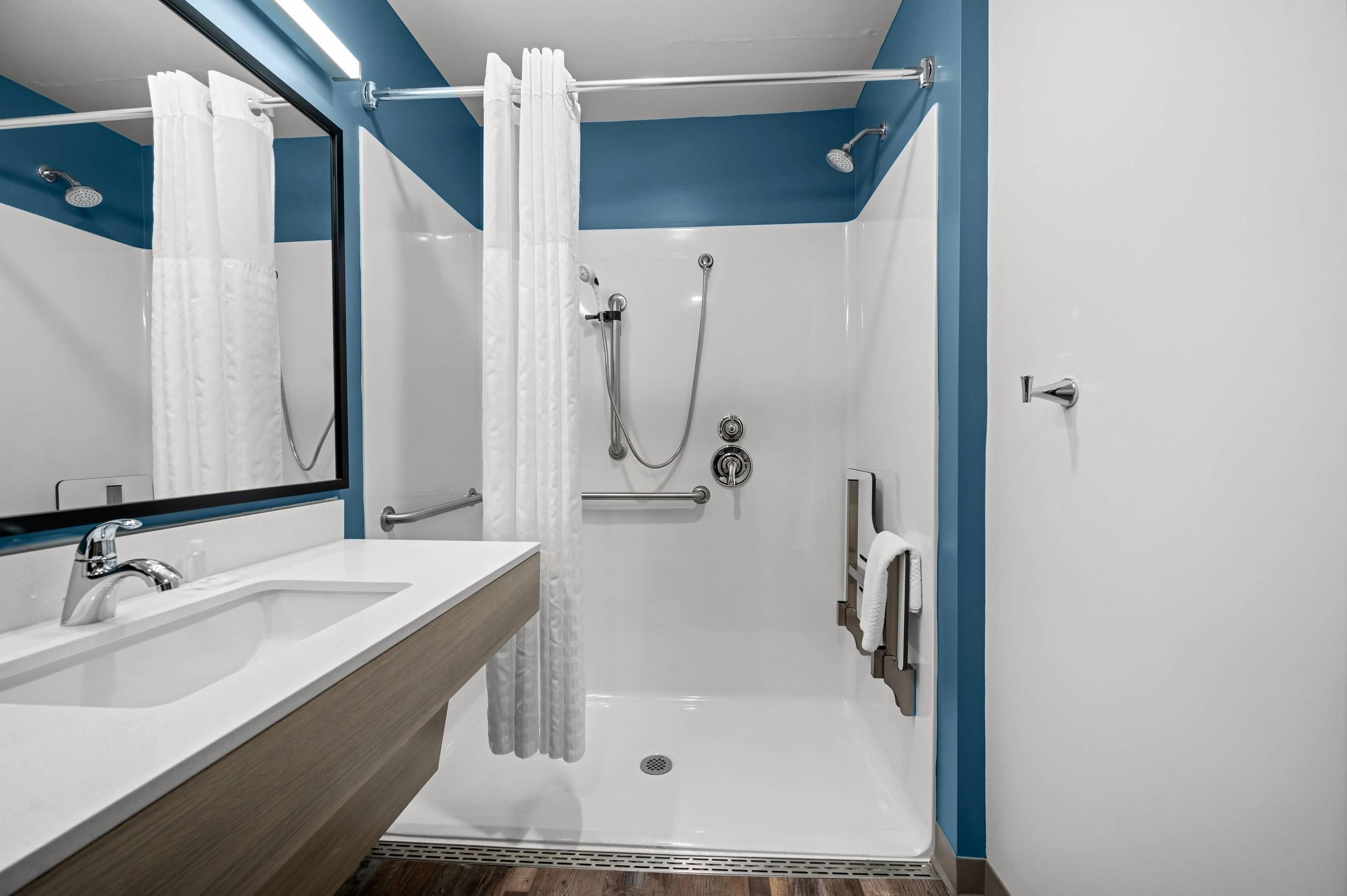 A modern bathroom with a shower, a sink, and a mirror.