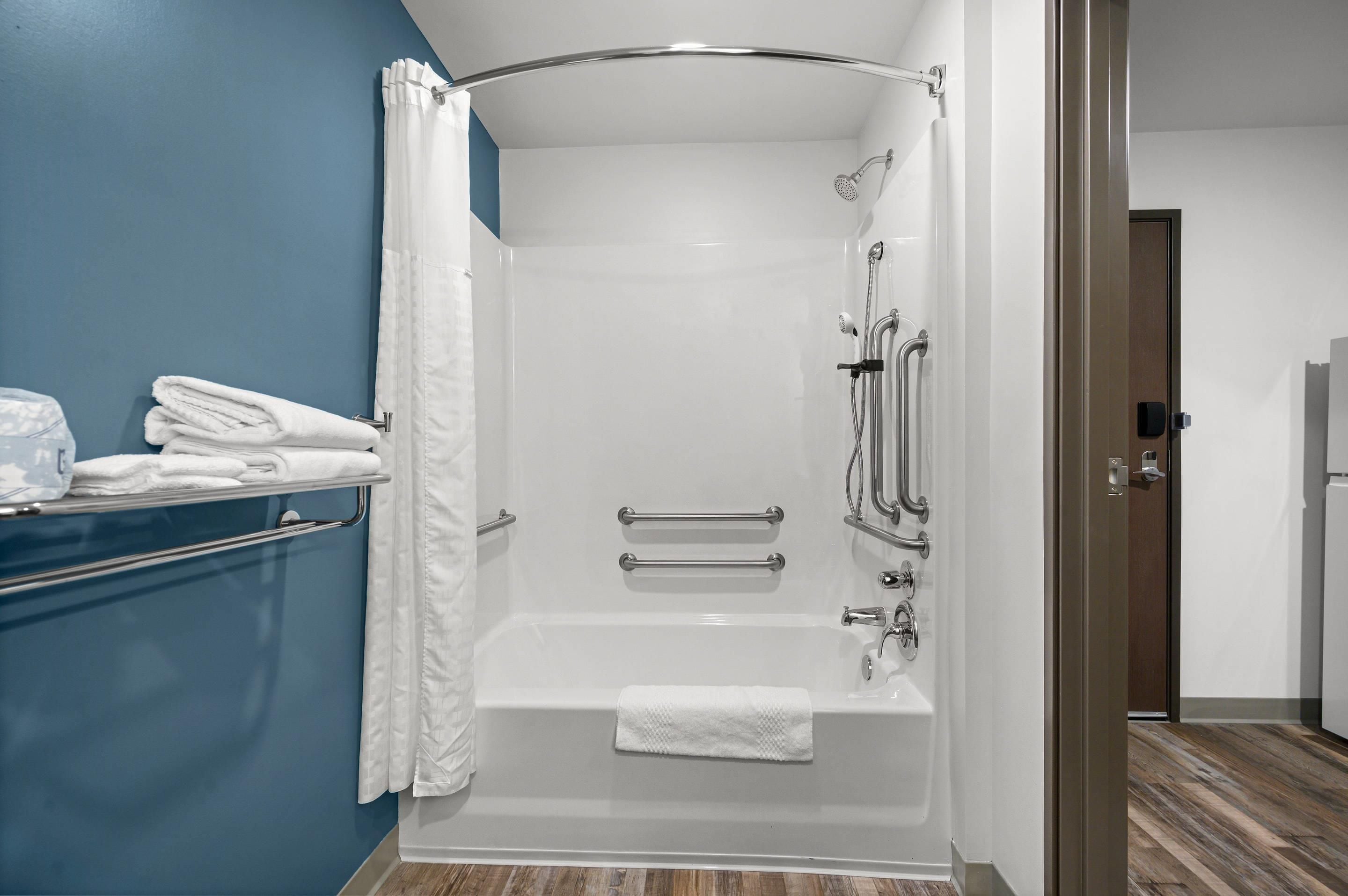 Une salle de bain moderne dotée d’une douche à l’italienne, de barres d’appui et d’un porte-serviettes.