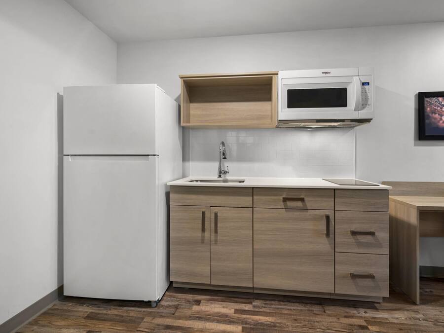 A compact kitchen with a white refrigerator, a microwave, and wooden cabinets.