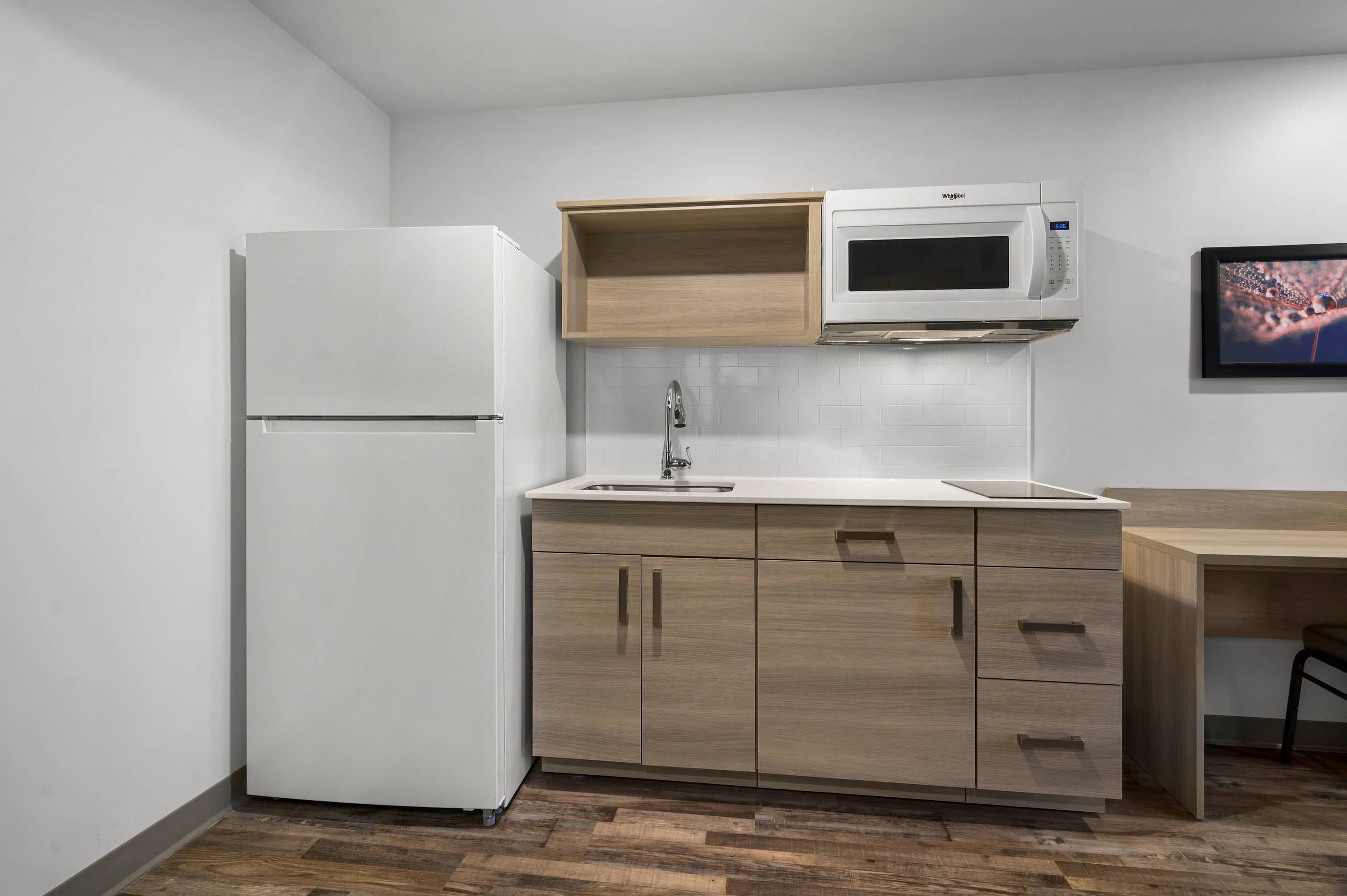 A compact kitchen with a white refrigerator, a microwave, and wooden cabinets.
