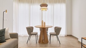 Un comedor moderno con una mesa redonda de madera, dos sillas grises y una lámpara colgante.