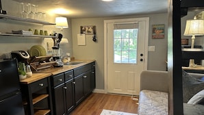 A compact kitchen with a wooden countertop, built-in cabinets, and a window.