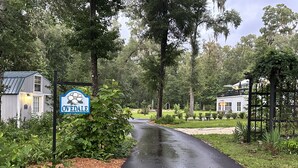 A rural road with a sign reading "Ovedale" surrounded by lush greenery and residential properties.