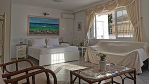 Ein Hotelzimmer mit Bett, Schreibtisch, Stuhl, einem Strandbild und einem Vorhangfenster.