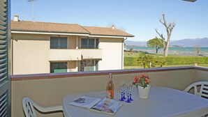 A balcony with a table, a bottle, and glasses, overlooking a residential area and a body of water. - Il Porticciolo P1 12 by Wonderful Italy (Sirmione)