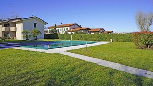 A residential area with a swimming pool, a well-maintained lawn, and houses with red-tiled roofs. - Il Porticciolo P1 12 by Wonderful Italy (Sirmione)