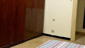 Una stanza con un armadio in legno, un tappeto a righe e una parete semplice.