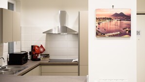 Een moderne keuken met een rvs afzuigkap, een spoelbak en een rode waterkoker.