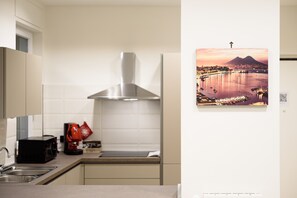 A modern kitchen with a stainless steel range hood, a sink, and a red kettle.