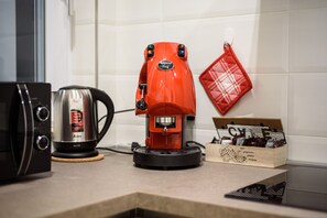 A kitchen with a red coffee machine, a kettle, and a box of tea bags.