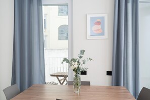 A dining area with a wooden table, grey curtains, and a framed picture on the wall.