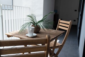 A wooden table with a white cup and saucer, a potted plant, and two wooden chairs.