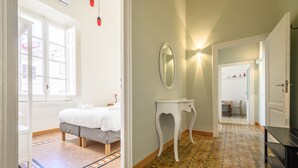 Habitació d'hotel amb llit, una taula petita, un mirall i un terra de rajola.