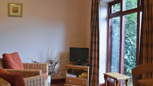 Sala de estar com móveis de vime, televisão e janela com cortinas.