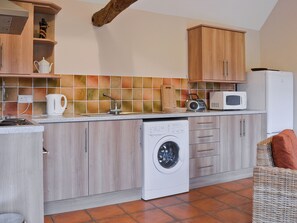 Una cocina compacta con lavadora, microondas y un mueble de madera.