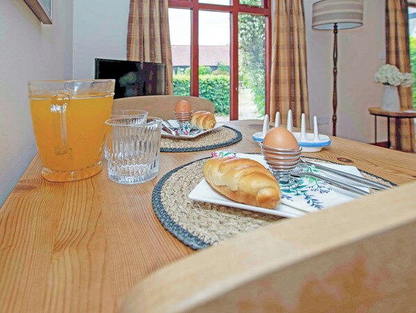 A breakfast table with a glass of orange juice, a croissant, a plate with a croissant, a plate with eggs, and a bread basket.