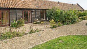 Un bâtiment avec un toit en tuiles, un revêtement en bois et une allée gravillonnée.