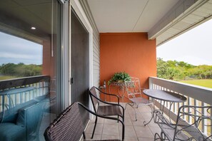 Un balcon agrémenté de meubles en osier, d’une petite table et d’une plante en pot.