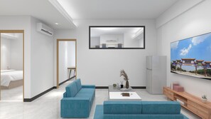 A modern living room with a large flat-screen TV, a sofa, a coffee table, and a TV stand with decorative items.
