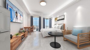 A modern hotel room with a bed, a sofa, a dining table, and a TV. - Foshan Laide Apartment (Foshan)