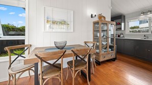 Un comedor con una mesa y sillas de madera, un aparador de vidrio con vajilla, y una ventana con vistas a zonas verdes.