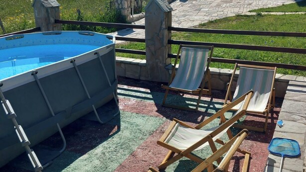 A pool area with lounge chairs and a stone wall. - Rocky Mountain Triple Room (Prisoje)