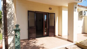 A building entrance with a door and shutters, a small outdoor area with a bench, and an air conditioning unit on the wall. - MareSole La Cinta - Two Bedroom Apartment, Sleeps 6 (San Teodoro)