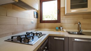 A kitchen with a gas stove, a window, and wooden cabinetry. - MareSole La Cinta - Two Bedroom Apartment, Sleeps 6 (San Teodoro)