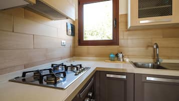 Een koelkast, een oven, een kookplaat, kookgerei, borden en bestek