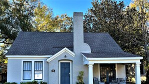 A single-story house with a gray roof, a chimney, and a front porch with outdoor seating. - Old Town Charmer Large all new renovation, walk to USM, Zoo and new Water Park! (Hattiesburg)