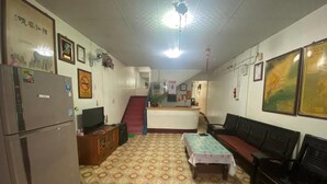 A living room with a patterned floor, a sofa, a table, a refrigerator, and a television. - WAYU HOUSE (Dawu)