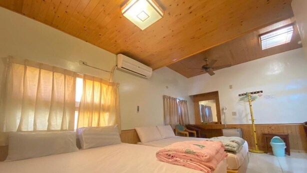 A hotel room with a wooden ceiling, a bed with white linens, a desk with a chair, and a window with curtains. - WAYU HOUSE (Dawu)