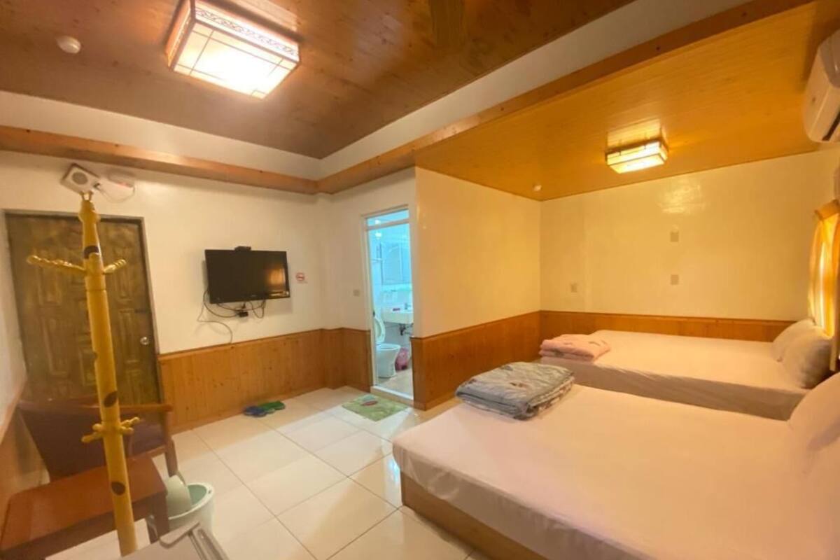 Habitación de hotel con dos camas, un televisor y techo de madera.