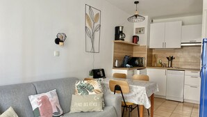 Un espace de vie compact comprenant un canapé gris, une table basse en bois et un coin repas avec une nappe blanche.