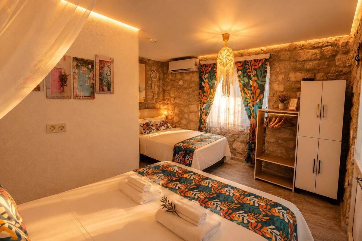 A room with two beds, a wardrobe, a small table, and a decorative wall.