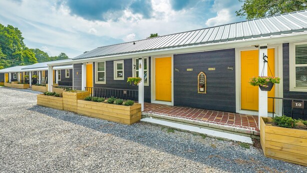 A row of single-story cabins with individual entrances, each featuring a small porch and a flower planter.