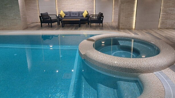 An indoor swimming pool with a circular hot tub, lounge chairs, and wall-mounted lighting. - WELLFORT HOTEL (Samarkand)
