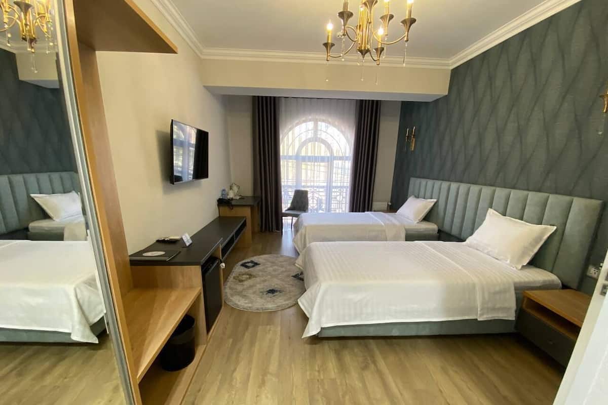 A hotel room with two beds, a TV, a desk, and a large mirror.