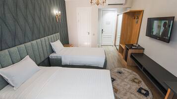 A hotel room with two beds, a TV, a wooden wardrobe, and a round rug.