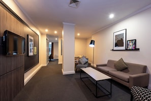 A modern living room with a sofa, a coffee table, and a TV mounted on the wall.