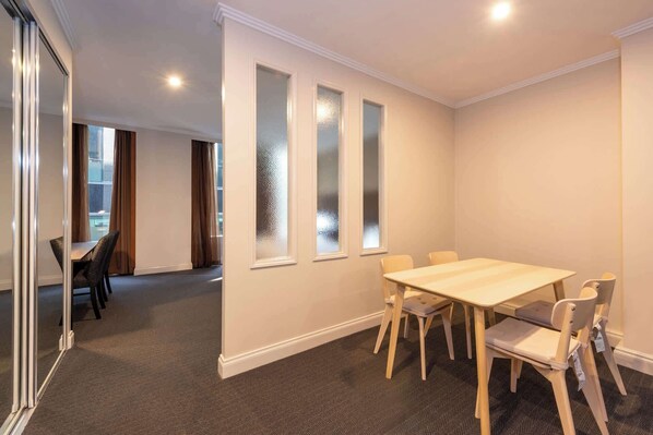 Un salón de conferencias con una mesa y sillas de madera, ventanas con vidrio esmerilado y piso alfombrado.