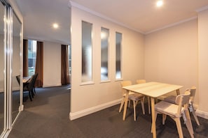 Une salle de conférence avec une table et des chaises en bois, une cloison en verre et un sol recouvert de moquette.