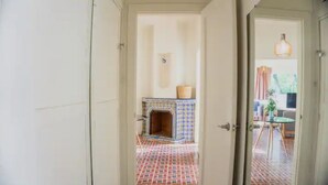 Un umbral abierto que da a un cuarto con piso de baldosas, chimenea con diseño y lámpara colgante.