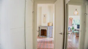 Un umbral abierto que da a un cuarto con piso de baldosas, chimenea con diseño y lámpara colgante.