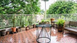 Une terrasse sur le toit, dotée d’un sol carrelé, de plantes en pot, d’une table ronde et d’un banc.