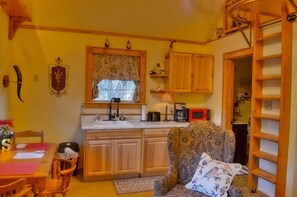 Una cocina acogedora con armarios de madera, un lavaplatos empotrado y una ventana con cortinas florales.
