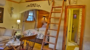 A cozy room with a loft bed, a wooden ladder, a small table with a vase, and a chair. - Aschenputtel Cottage (#4) (Fredericksburg)